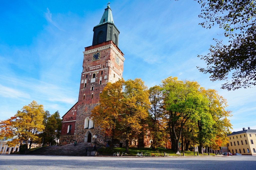 Turun tuomiokirkko kohoaa syksyn sävyttämän kaupunkimaiseman keskellä kuvastaen turkulaista kulttuuria, paikallista identiteettiä ja Turun murteen juuria.